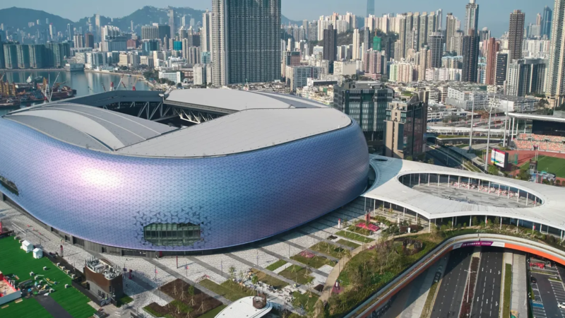 A modern architectural rendering of Hong Kong's Kai Tak smart city skyline integrated with blockchain digital overlay graphics.