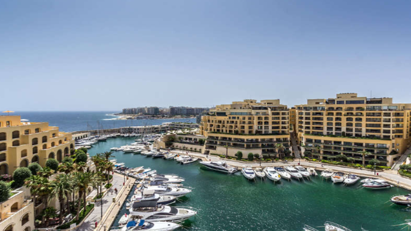 Architectural skyline of Portomaso Marina and Valletta harbor with digital blockchain network overlay graphics.