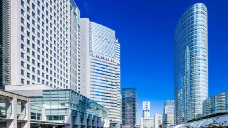 Futuristic skyline rendering of Tokyo's Takanawa Gateway City smart district integrated with digital blockchain network visual overlay.