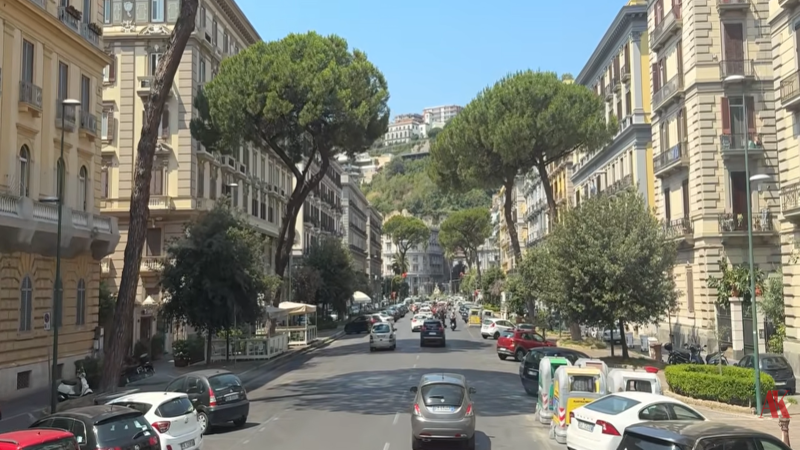 An aerial view of the bustling Port of Naples and historic Spaccanapoli street, overlaid with blockchain networks and institutional stablecoin data flows representing deep value RWA investment.