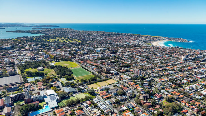 Aerial view of Bondi Beach and coastal cliffs in Sydney's Waverley Council, overlaid with institutional digital security token graphics and blockchain nodes.